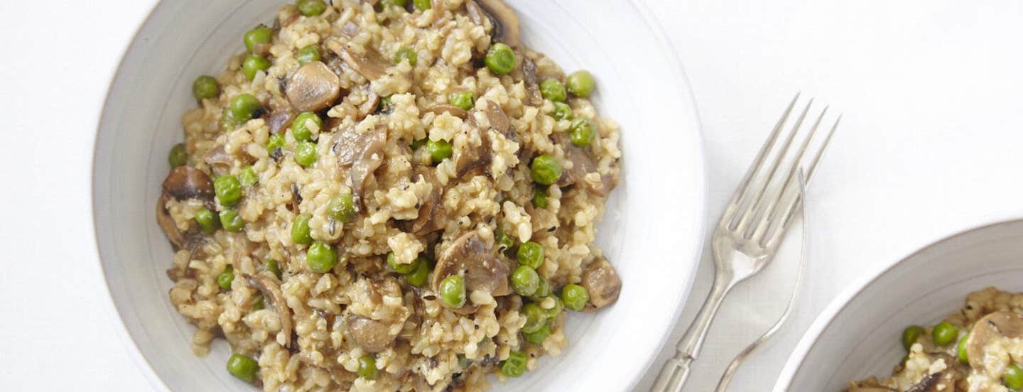 Top-down view of Mushroom and Green Pea Risotto on a white plate on a white background