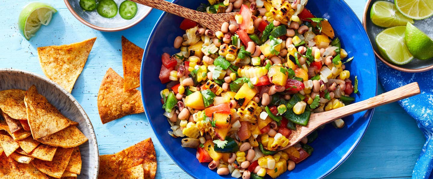 Peach-Corn Salsa in a large bright blue bowl with Chili-Lime Chips in another bowl to the side