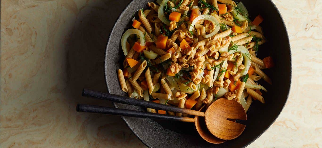 Penne with Butternut Squash and Fresh Fennel in a gray bowl with wooden serving spoons