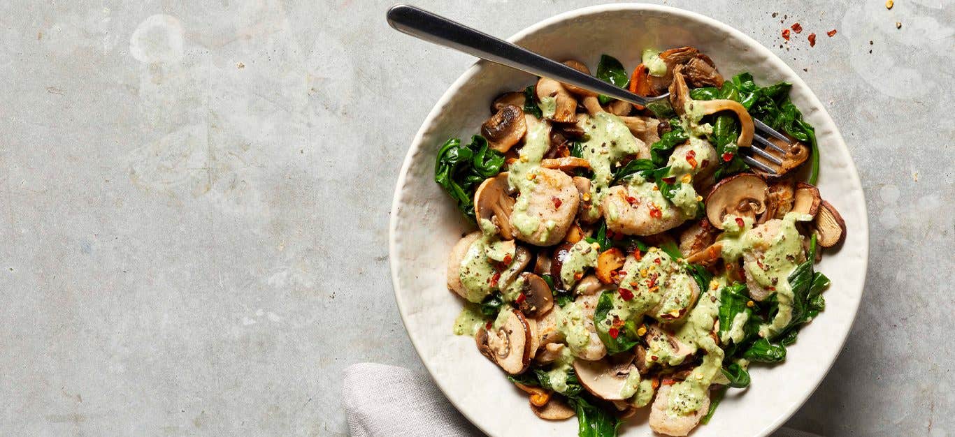 Potato Gnocchi with Mushrooms and Greens in a white bowl with a metal fork