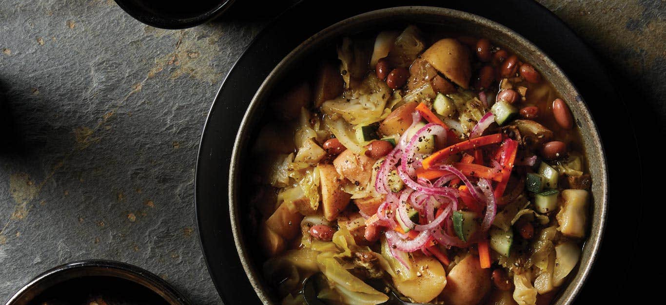 Instant Pot Cabbage and Potato Soup with Pickled Veggies in a gray ceramic bowl against a stone background