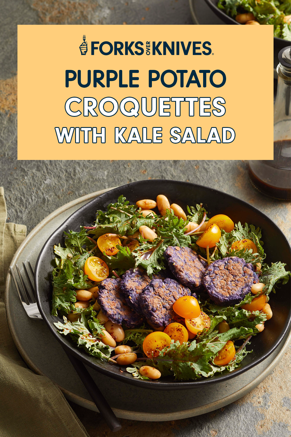 A black bowl filled with green salad, white beans, yellow cherry tomatoes, and slices of purple potatoes. Text reads, "Purple Potato Croquettes with Kale Salad"