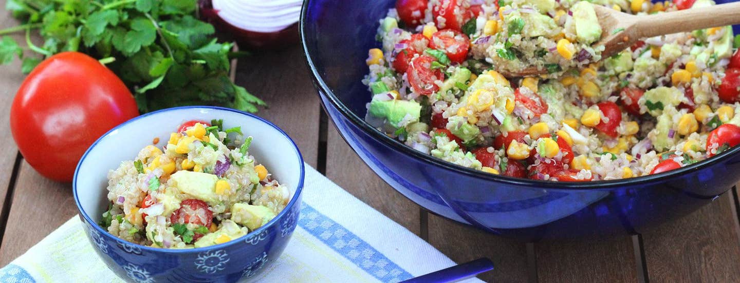 Quinoa, Corn, and Avocado Salad in a blue glass bowl with one serving in a smaller blue bowl to the side