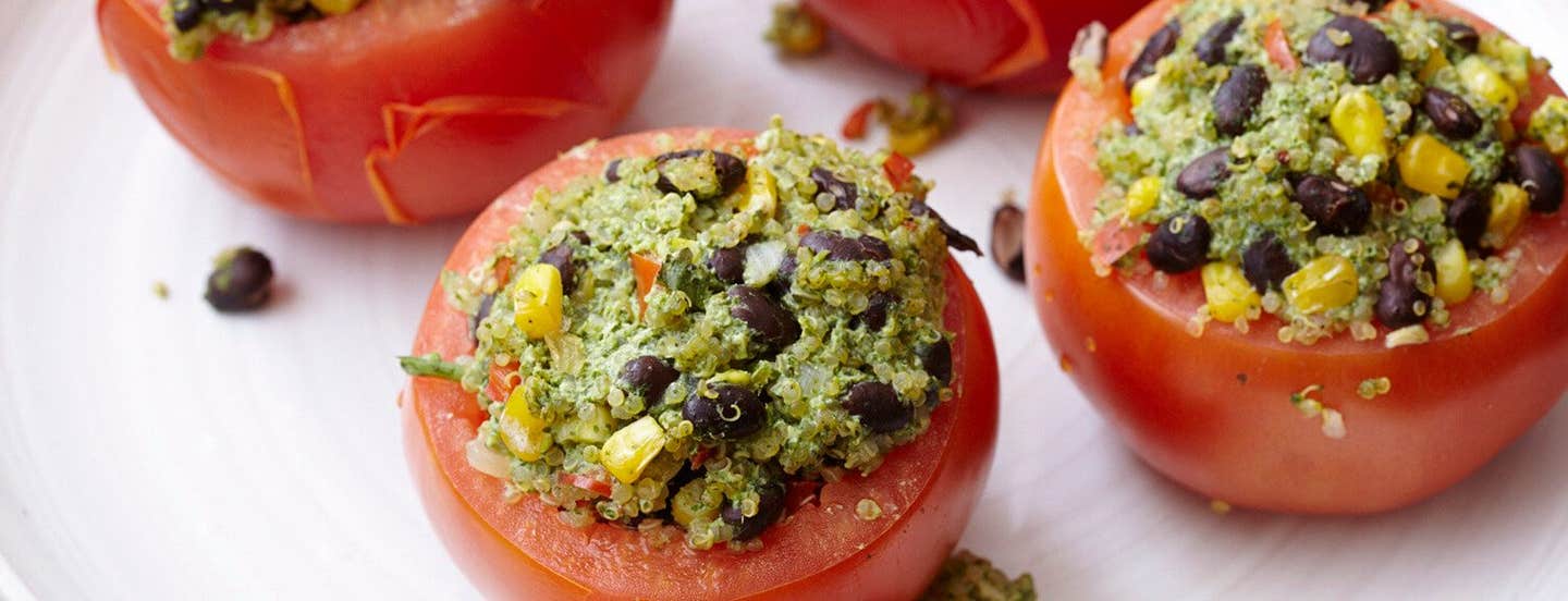 A close-up shot of two Quinoa-Stuffed Tomatoes with Spicy Cilantro Pesto on a white counter