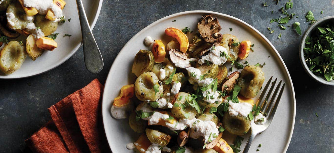 Gluten-Free Gnocchi with Roasted Vegetables on a white plate with metal fork and orange napkin