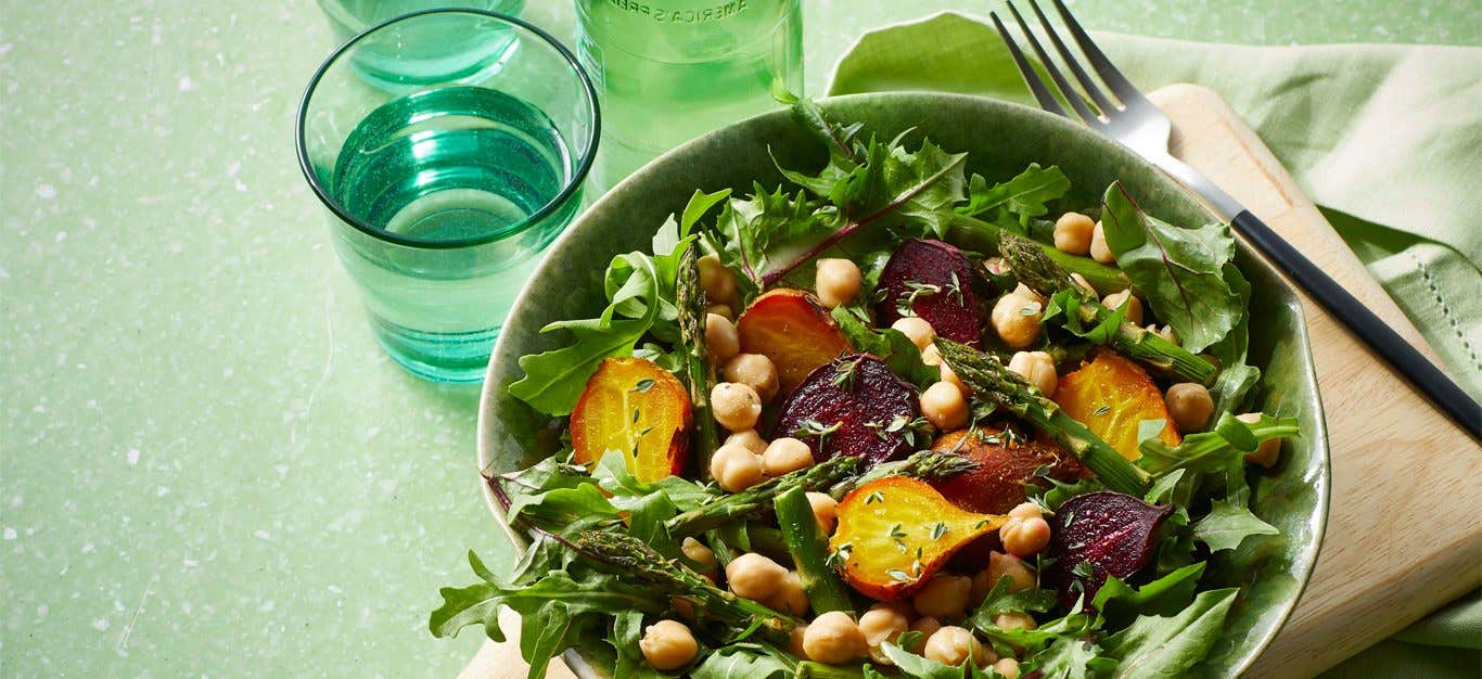 Dandelion Greens Salad with Roasted Baby Beets in a white bowl against a green background