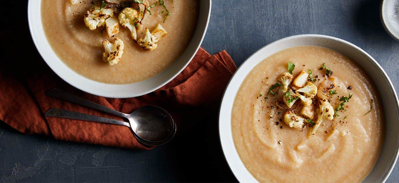 Roasted Cauliflower Soup in white bowls garnished with cauliflower florets