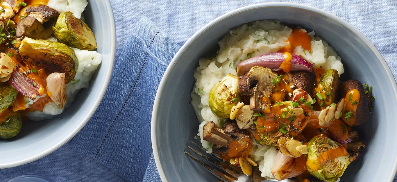 Roasted Veggie Bowls with Garlic Mashed Potatoes and vegan queso sauce in light blue ceramic bowls against a light blue linen tablecloth