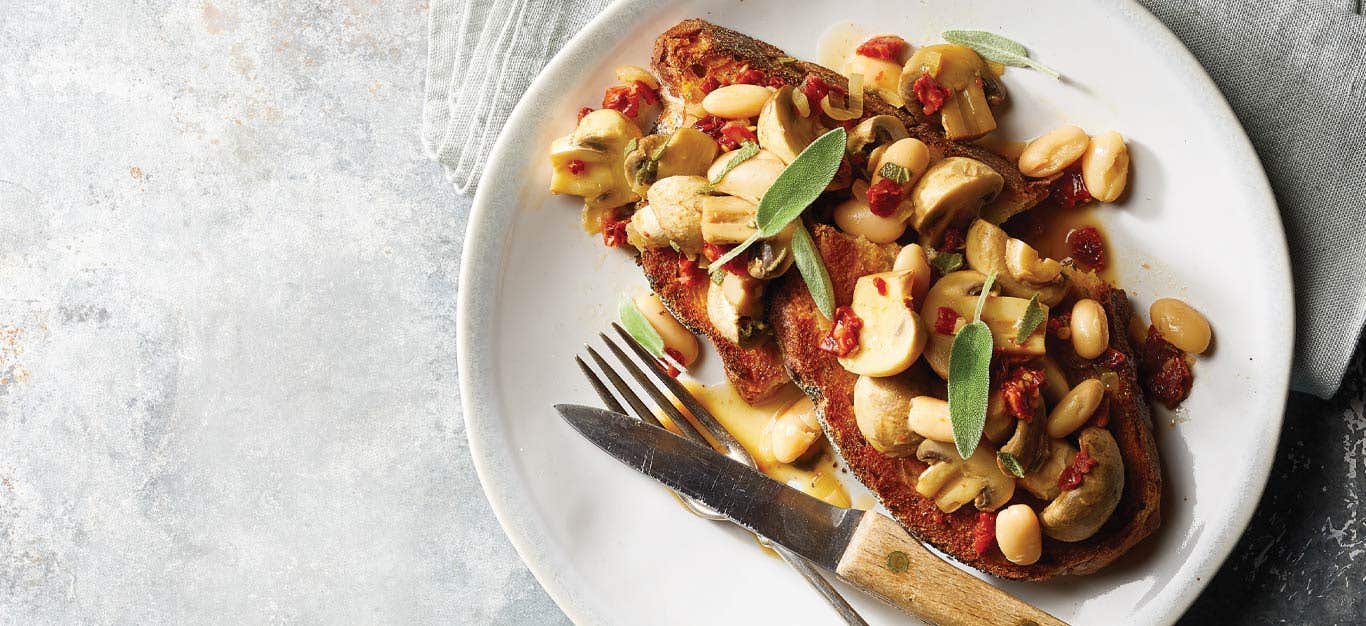 10-Minute Sage and Mushroom Tartine on a white plate with a knife and fork