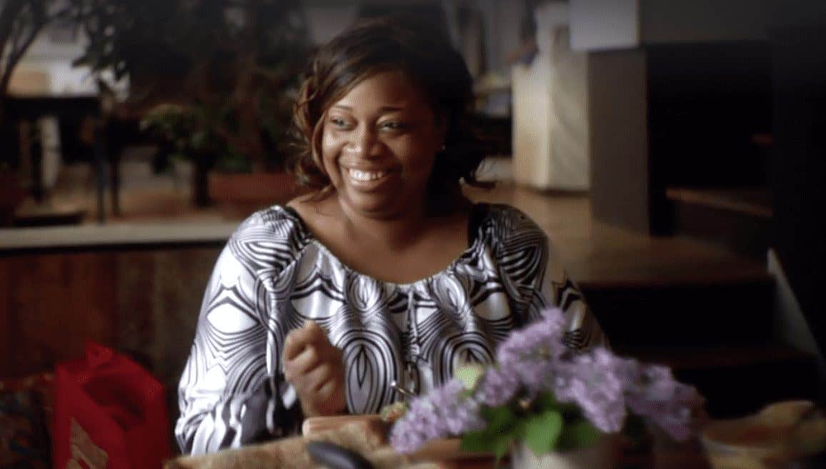 African American woman from the FOK movie in her home looking happy