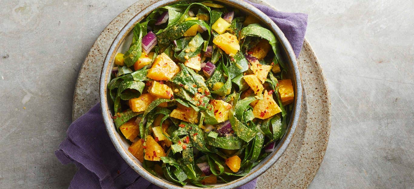 Spicy Collard Slaw in a ceramic bowl on a gray countertop