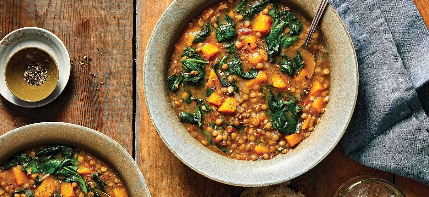 Lentil and Spinach Soup in a beige ceramic bowl on a wooden tabletop