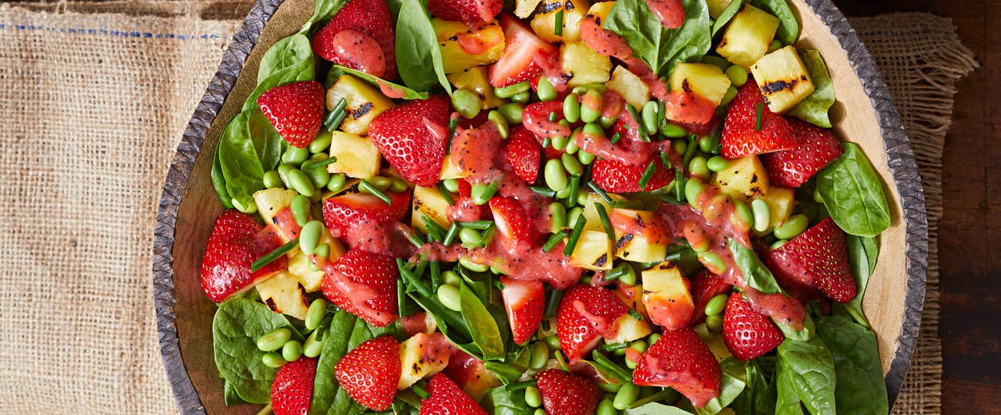 Spinach, Pineapple, and Strawberry Salad in a rustic homemade ceramic bowl on a piece of hessian