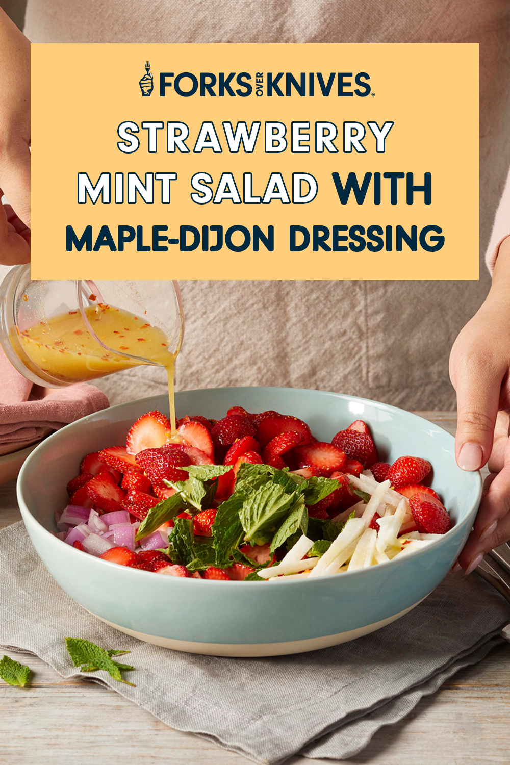 An unidentified woman standing in front of a colorful bowl of salad pouring a dressing into the bowl. A text box reads, "Strawberry-Mint Salad with Easy Maple-Dijon Dressing"