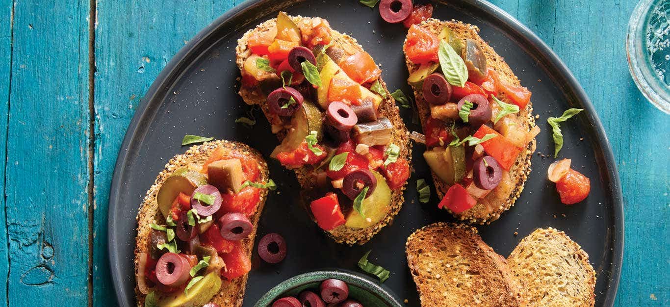 Ratatouille Bruschetta on a black plate on a turquoise tabletop