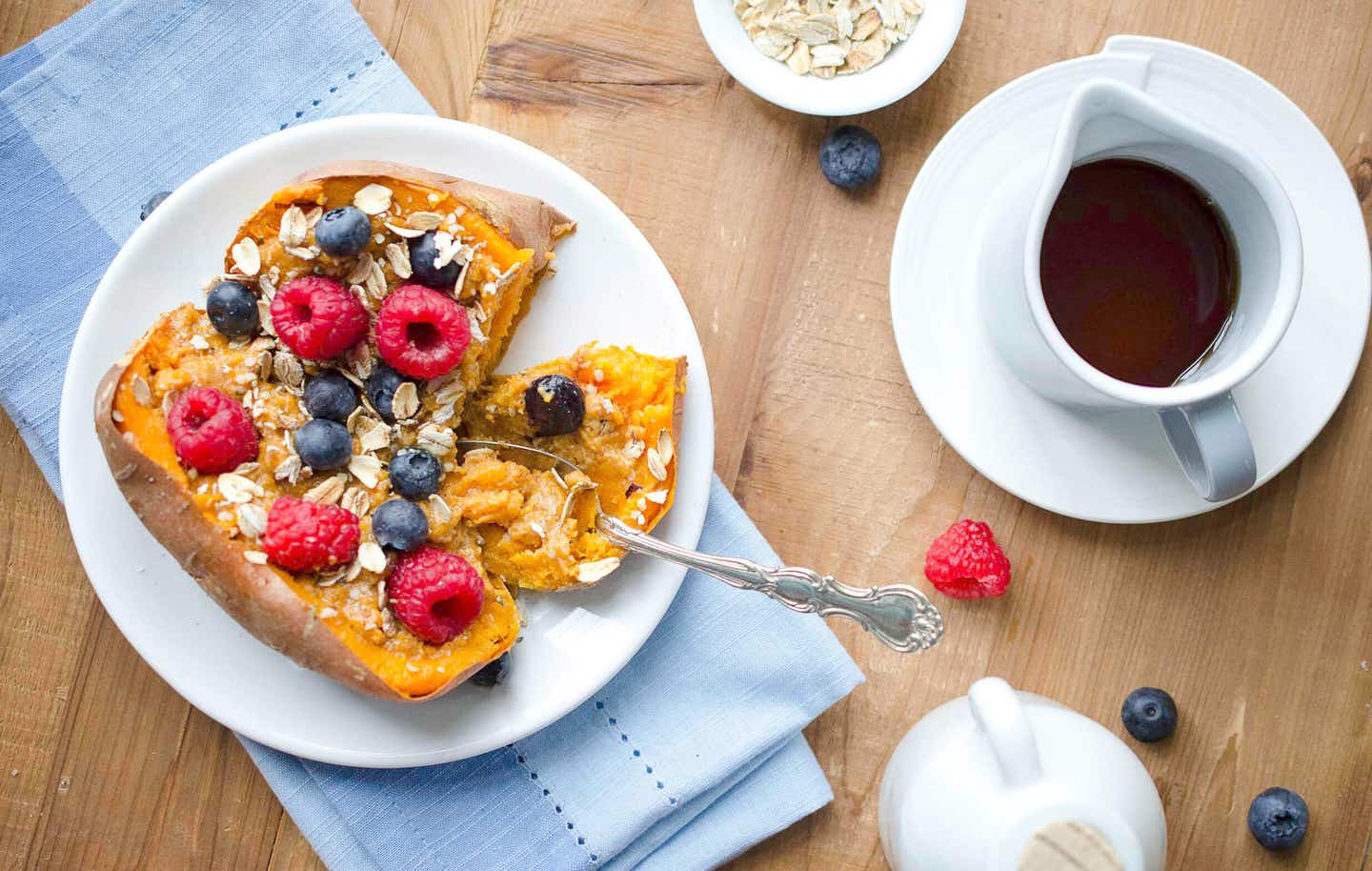 A baked sweet potato topped with oats and fresh berries