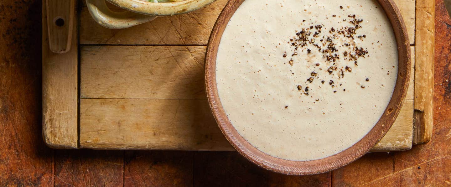 Tahini Dipping Sauce in a small handmade ceramic bowl on an old wooden chopping board