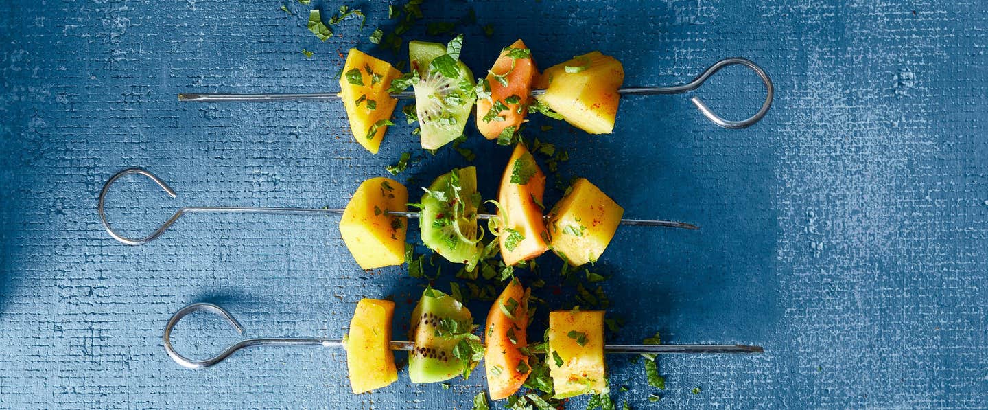 Three colorful Thai Fruit Skewers with Coconut and Lime against a blue background