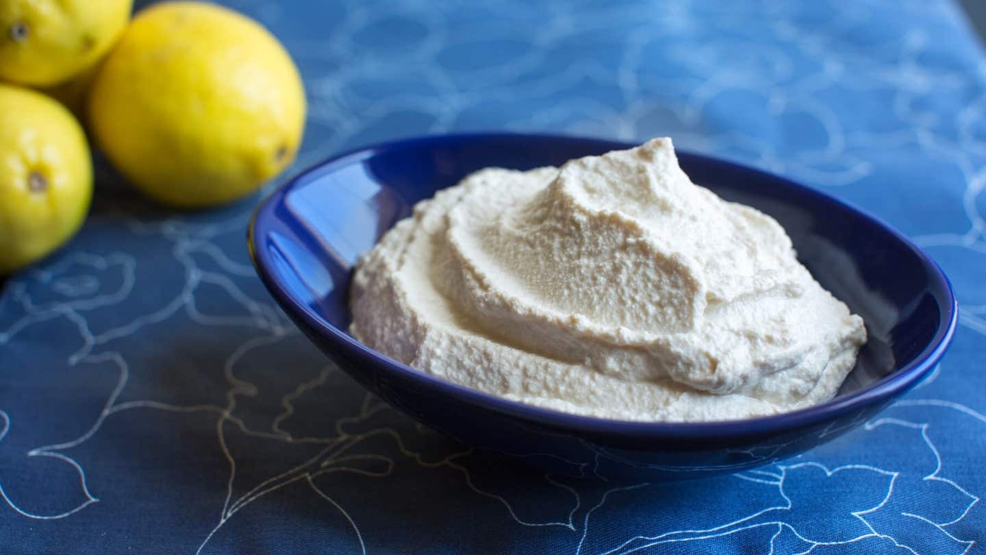 Tofu Sour Cream in a blue bowl with a lemon in the background