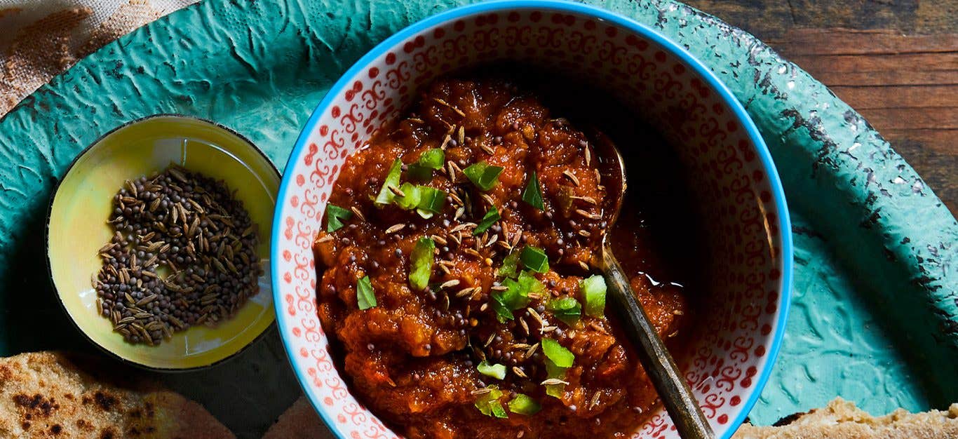 Bold red tomato chutney served in a teal stoneware bowl