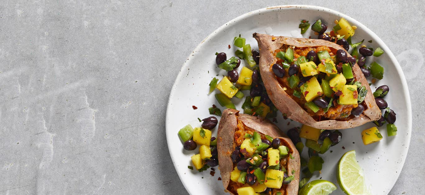 Caribbean Loaded Sweet Potatoes on a white plate against gray countertop