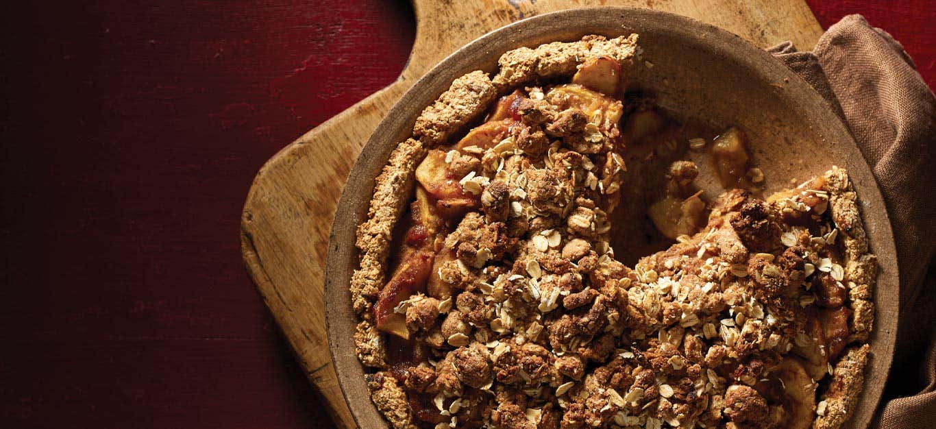 Vegan Apple Pie in a pie tin on a wooden cutting board