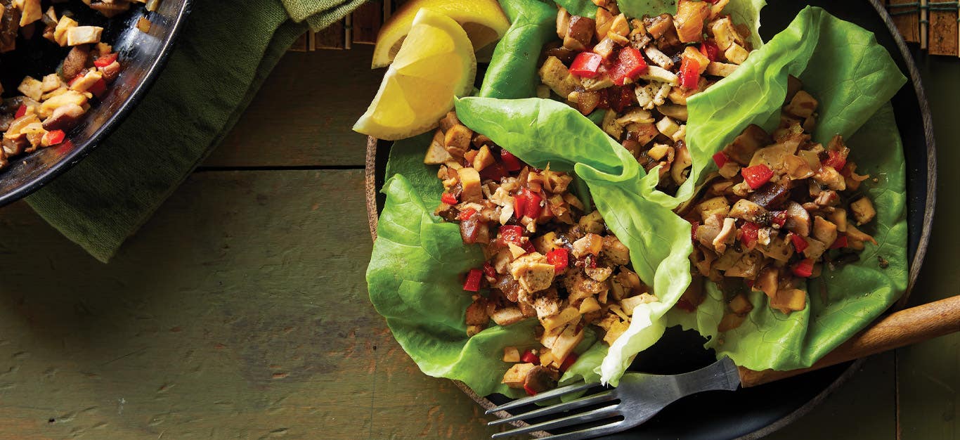 Vegan Sisig in lettuce cups on a dark green wooden background