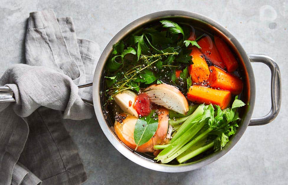 Pot of homemade vegetable broth featuring carrot chunks and celery