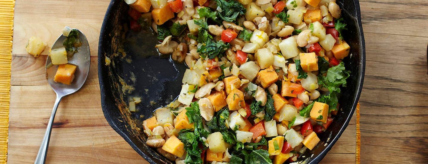 Vegetable White Bean Hash in a cast-iron skillet on a wooden chopping board