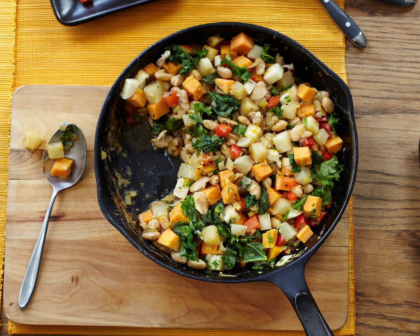 Vegetable White Bean Hash in a cast-iron skillet on a wooden chopping board