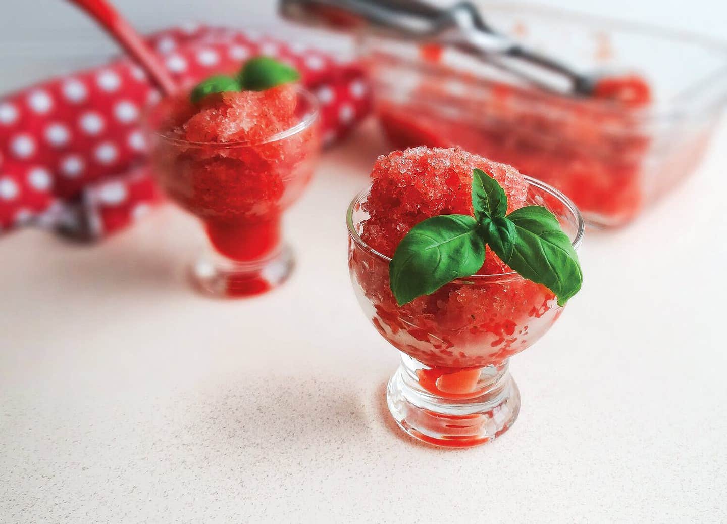 Two servings of Watermelon-Basil Ice in short-stemmed glasses with a large dish of the ice in the background