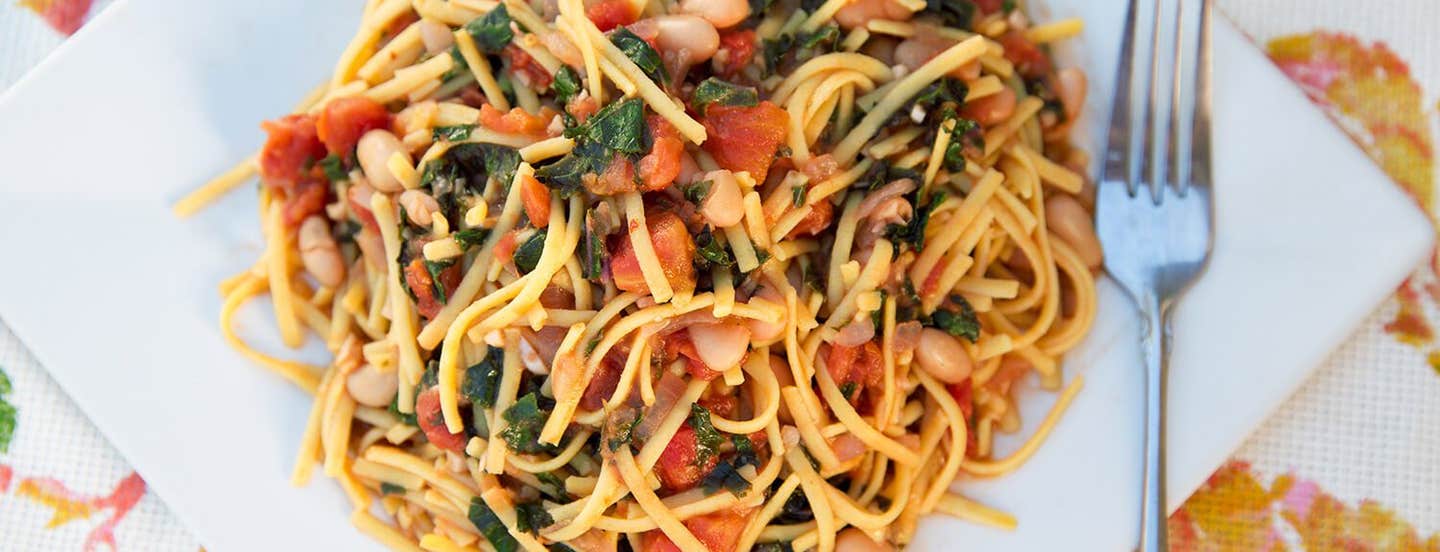 A white, square plate of White Beans with Greens, Garlic and Tomato