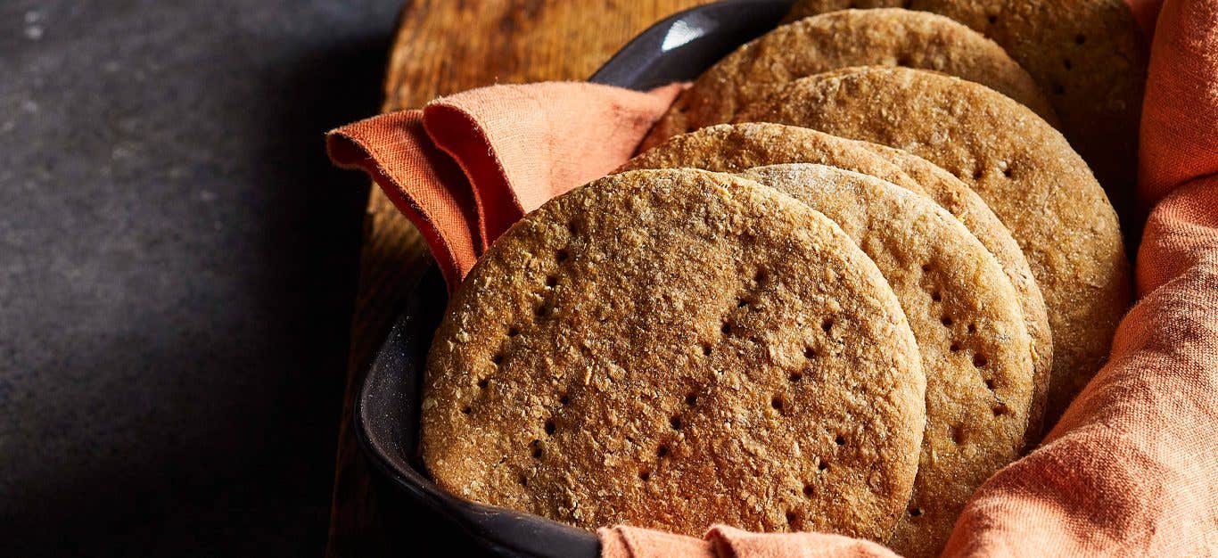 Whole Wheat Sandwich Thins stacked in a line on a peach colored dishcloth inside a serving tray