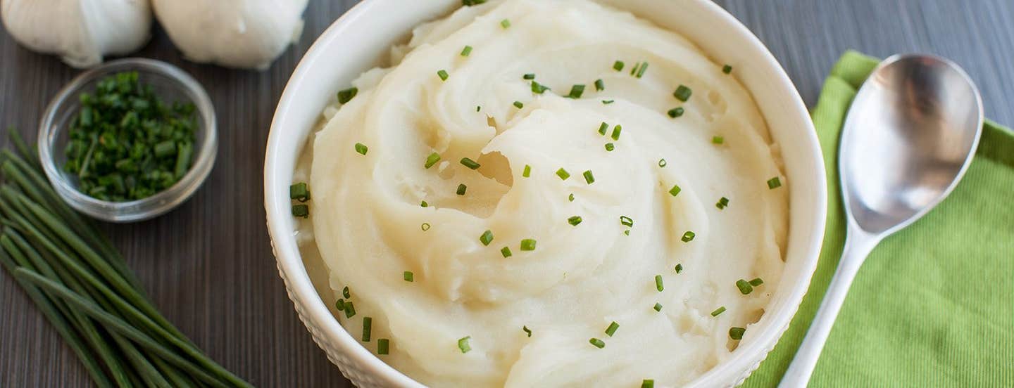 Vegan Mashed Potatoes in a white bowl with a garnish of chives