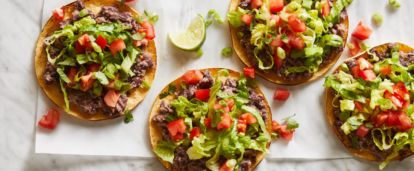 Quick Black Bean Tostadas on parchment paper on a marble counter with a lime wedge