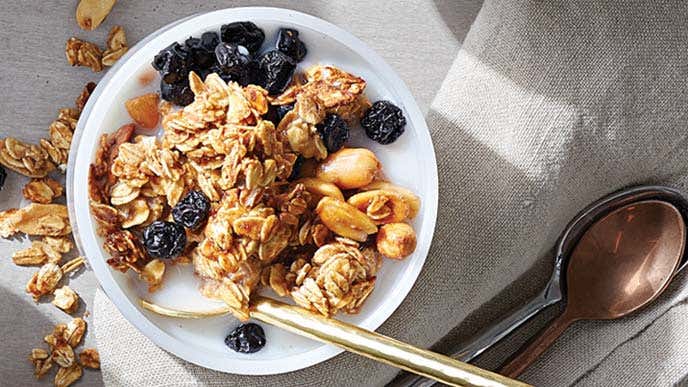 Peanut Butter-Blueberry Granola in a small white bowl with a metal spoon