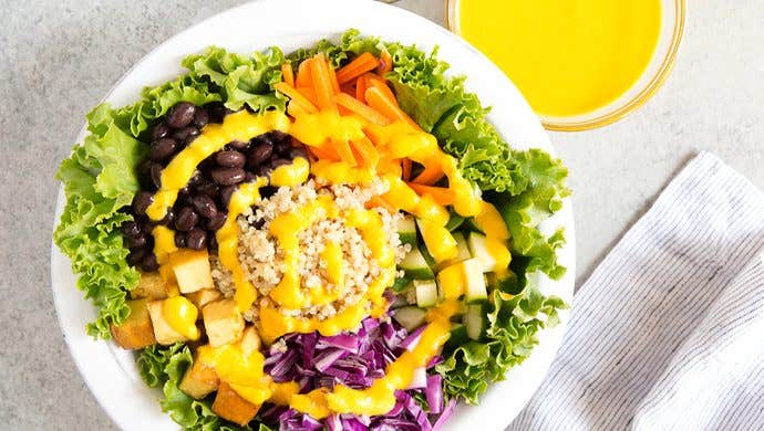 24-Carrot Gold Dressing in a small bowl next to a larger grain bowl drizzled with the dressing