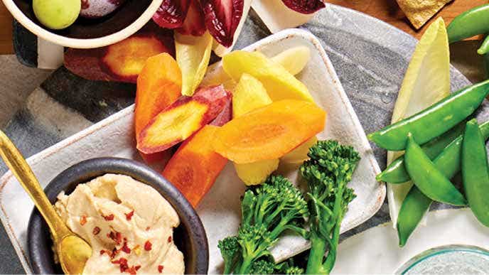 Classic Crudités with a small bowl of hummus sprinkled with chili flakes