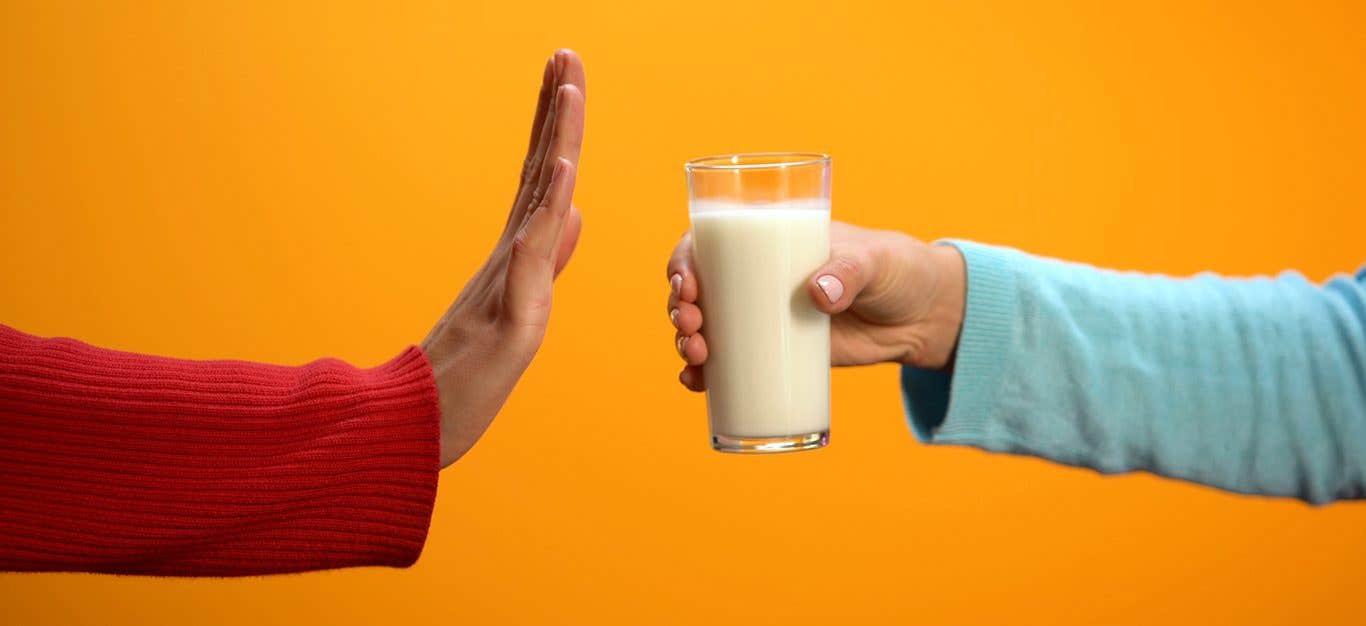 One hand offers a glass of milk, while another hand has its palm vertical in the stop motion