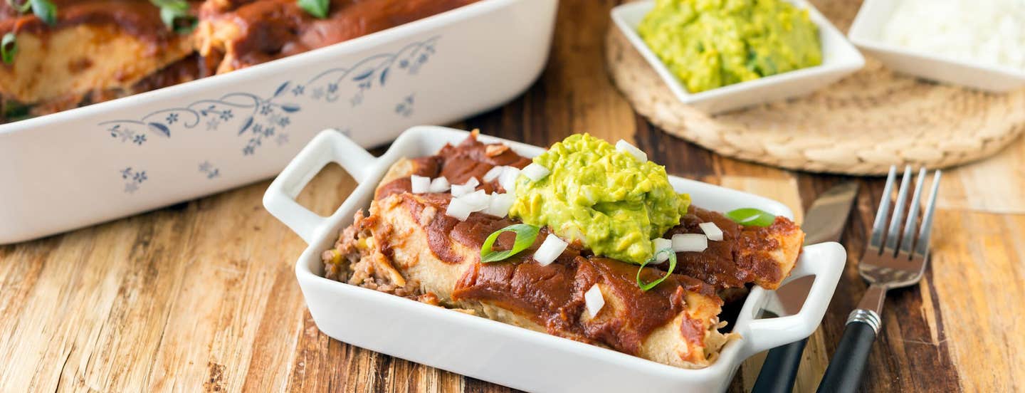 Bean & Corn Enchiladas topped with guacamole and sliced green onions