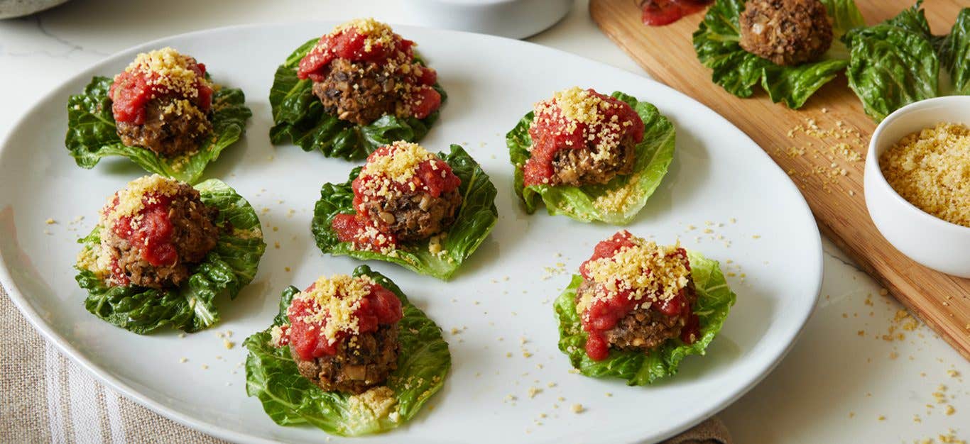 Half a dozen Fancy Vegan Meatballs served in small lettuce boats on a large white platter