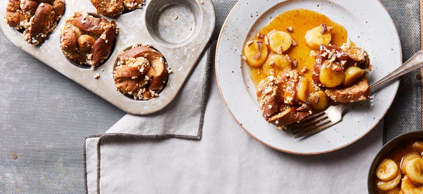 Crispy French Toast Cups with Bananas Foster Topping on a plate next to a muffin tray filled with the mixture, one serve per muffin tray