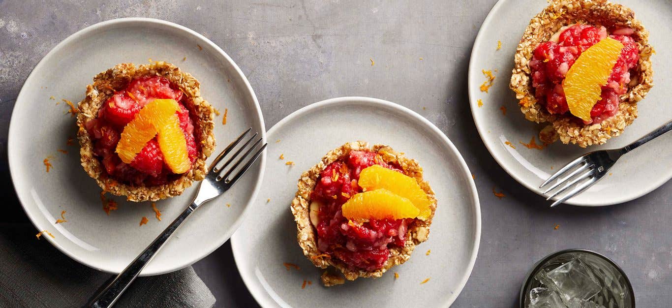 Mixed Fruit Tartlets with Raw Date and Nut Crust on white plates with metal forks