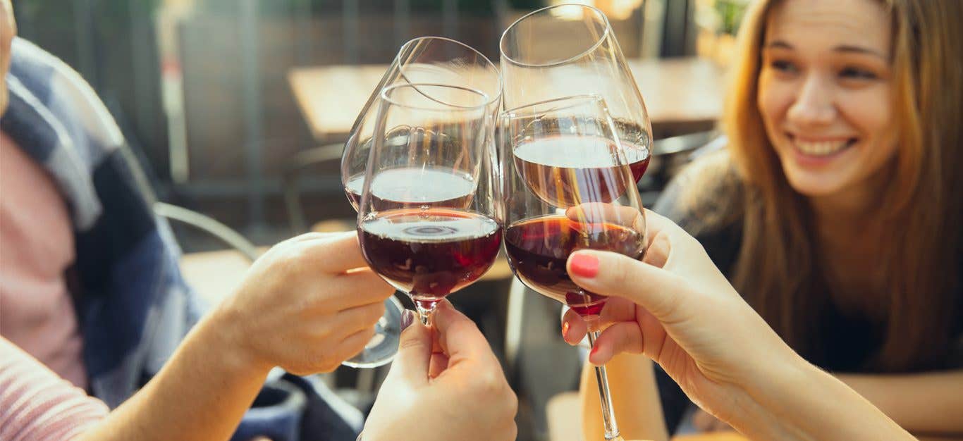 Young people clinking glasses of wine together in cheers