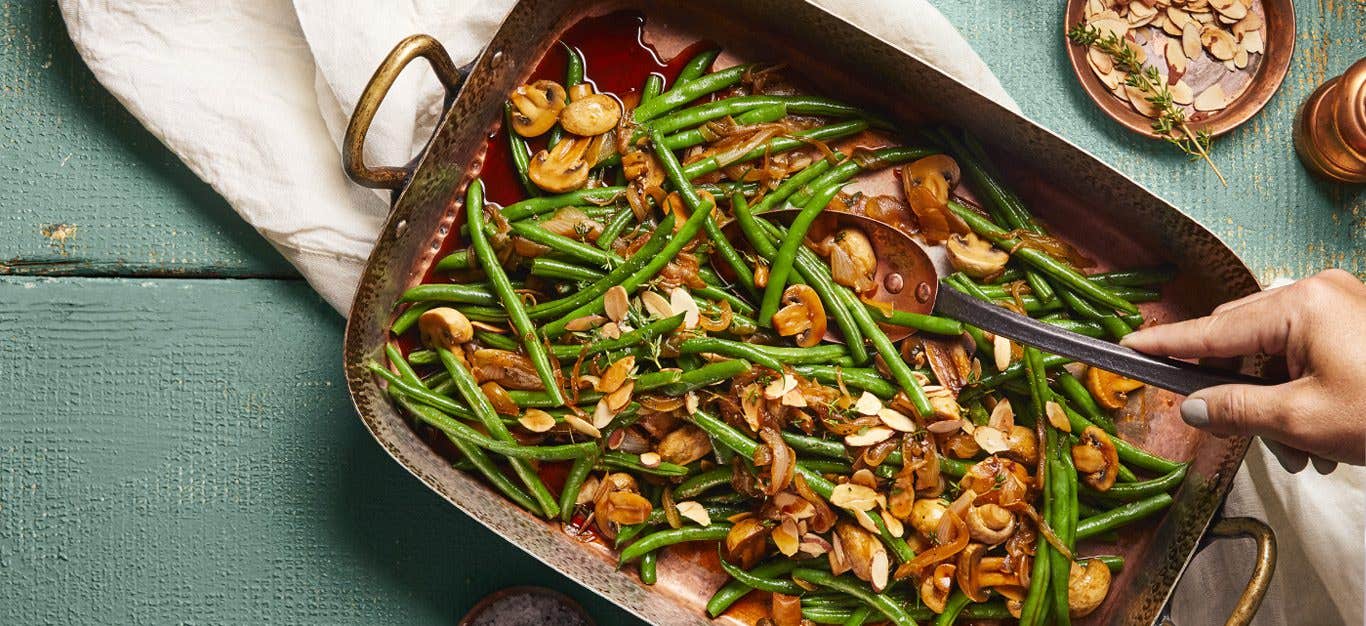 Skillet Green Beans with Caramelized Onions and Mushrooms in a serving tray on a blue table