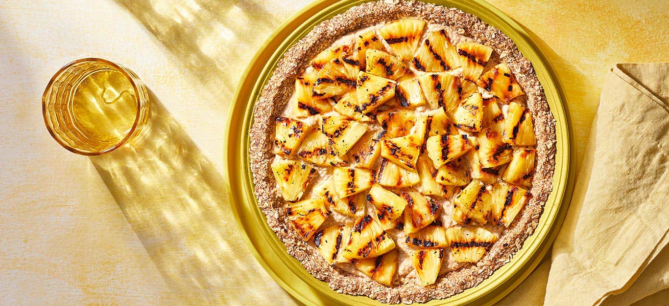 Grilled Pineapple Pie in a yellow pie tin against a yellow tabletop