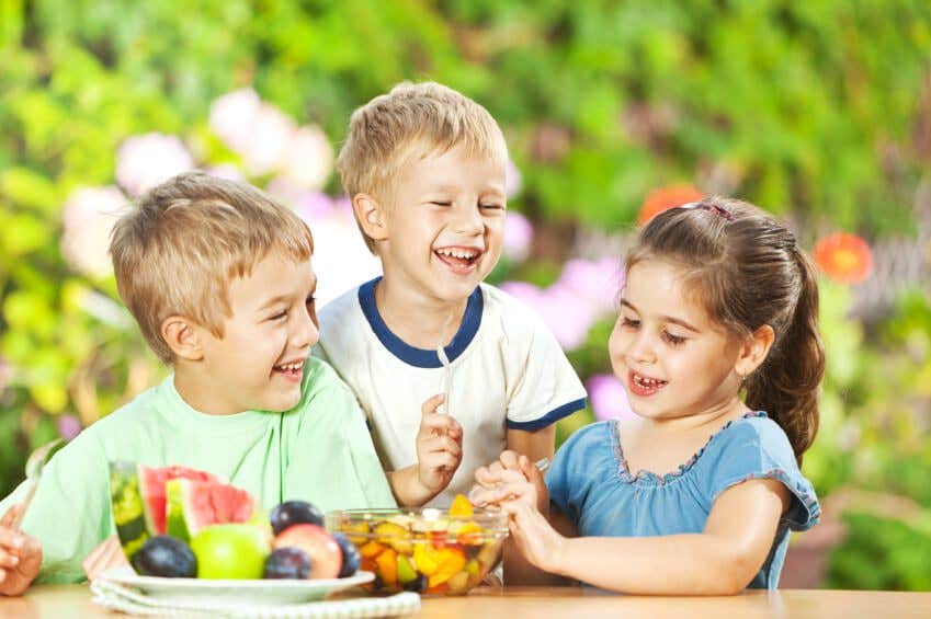 Three young children eating fruit salad