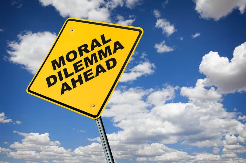 Looking up at a yellow road sign against the sky. The sign reads, "Moral Dilemma Ahead."