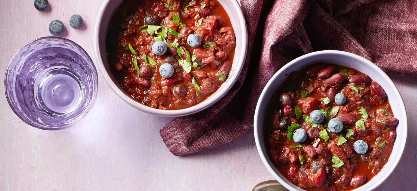 kidney bean chili blueberries in white bowls with a purple cloth napkin