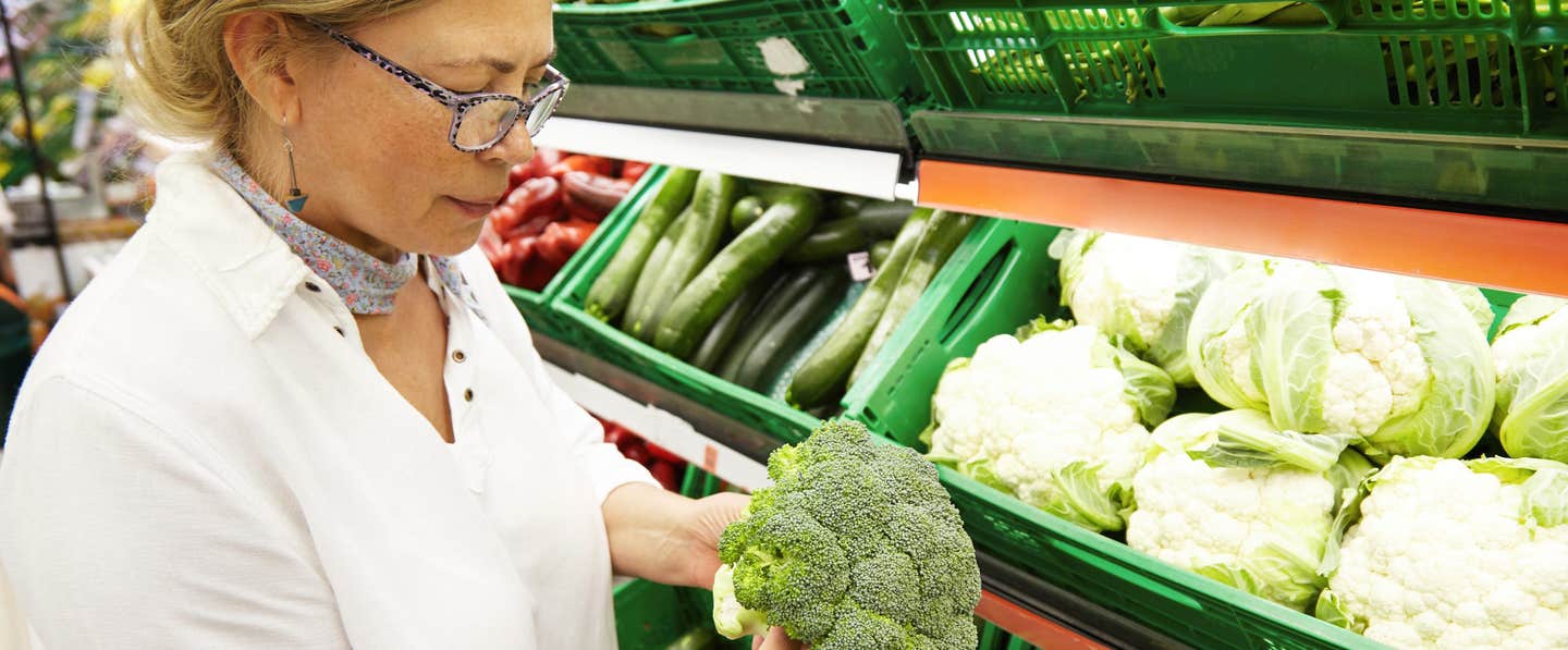 Woman looking at a head broccoli in the supermarket